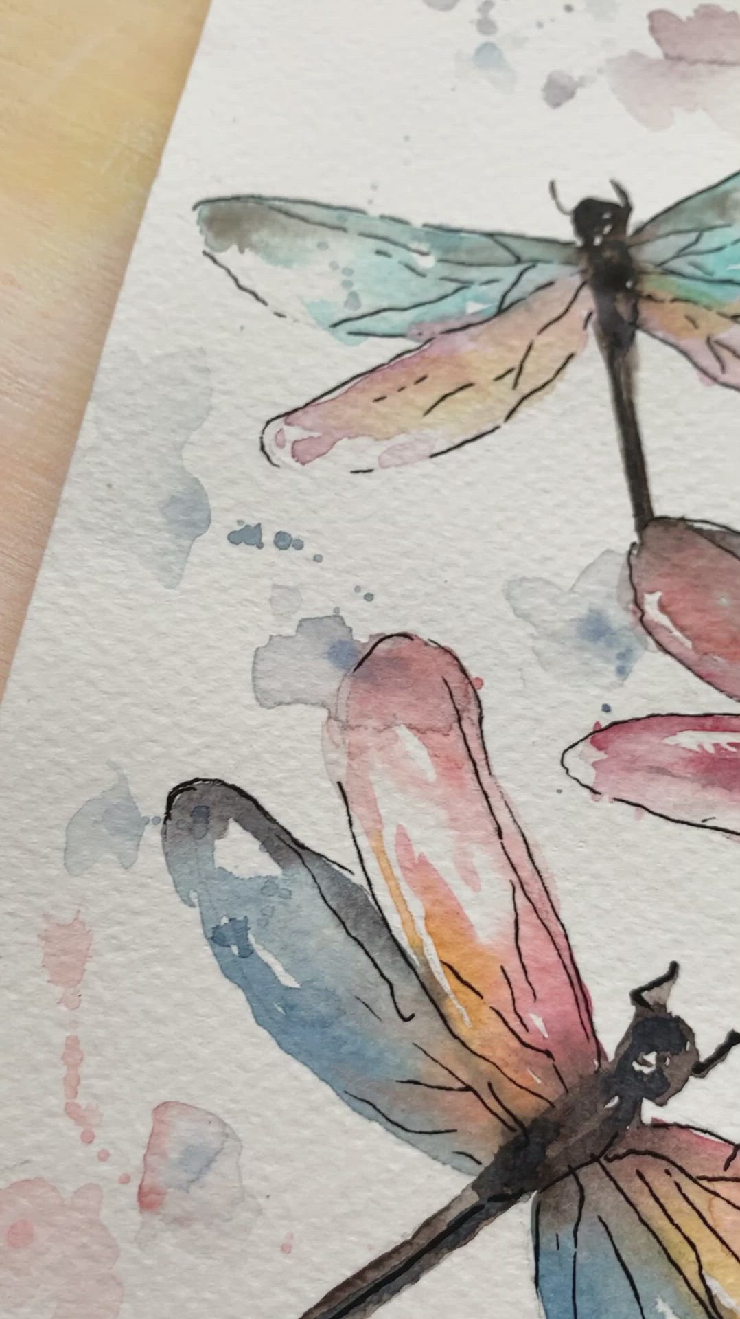 This may contain: three watercolor dragonflys sitting on top of a piece of paper