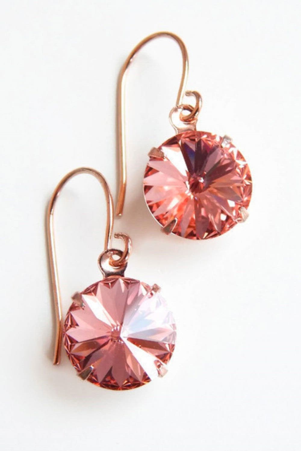 This contains: rose gold crystal earrings in peach