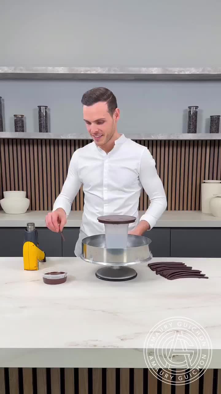 This may contain: a man standing in front of a cake on top of a white counter next to other items