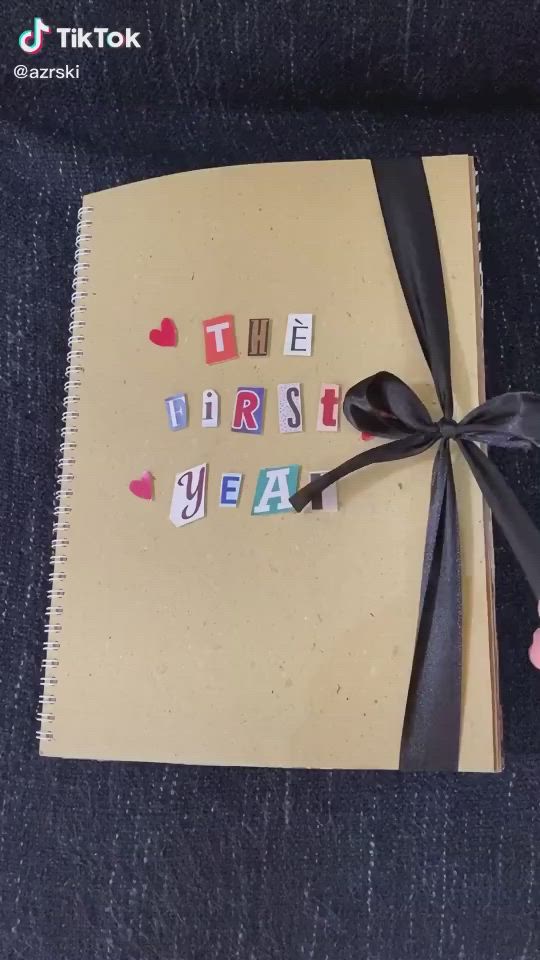 This may contain: an open notebook with the words first year written in small letters on it, tied to a black ribbon