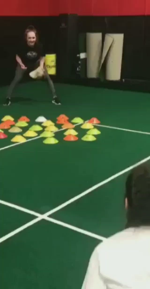 This may contain: two people are playing tennis on a green court with yellow and orange balls in the middle