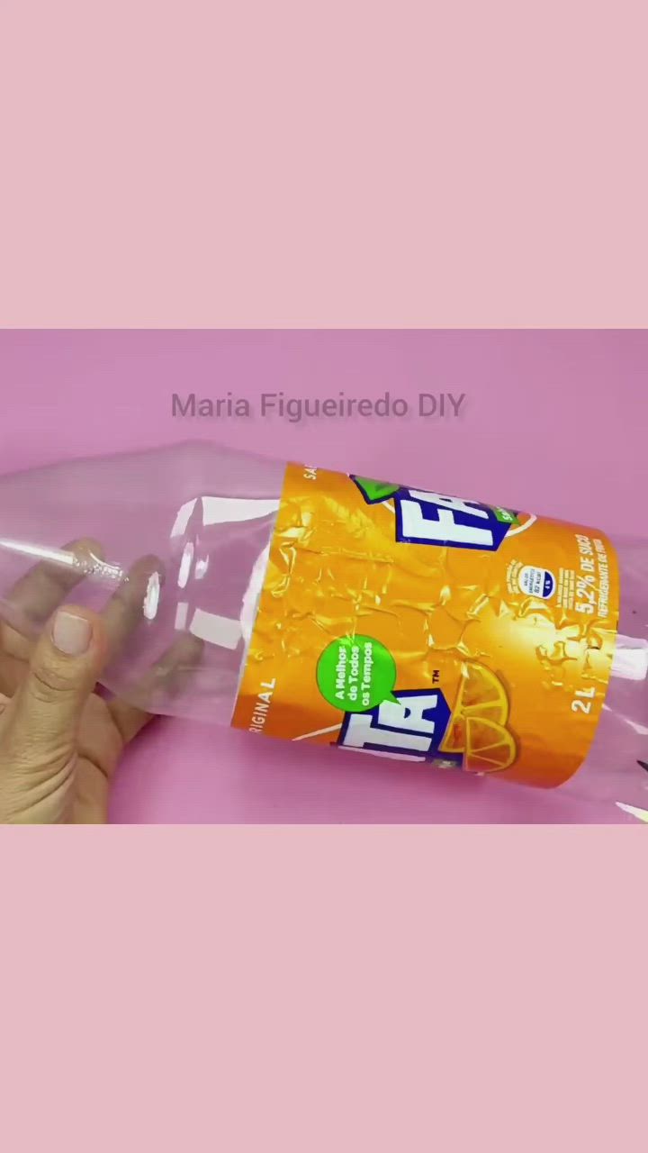 This may contain: a hand is holding a plastic bottle filled with liquid on a pink background and the bottom half of it being held by someone's hand