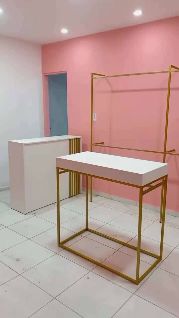 This may contain: an empty room with pink walls and a gold frame on the floor in front of a white counter