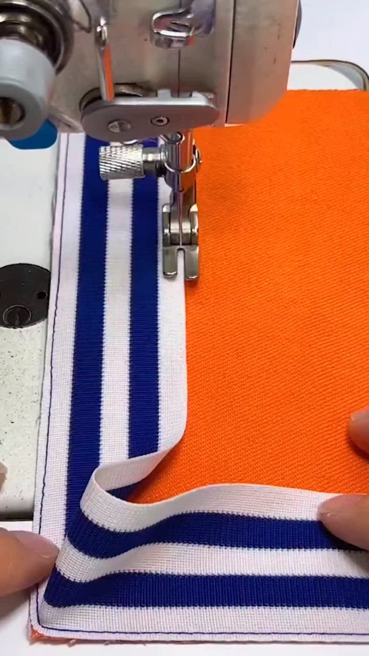 This may contain: someone is using a sewing machine to sew on a blue and white striped fabric