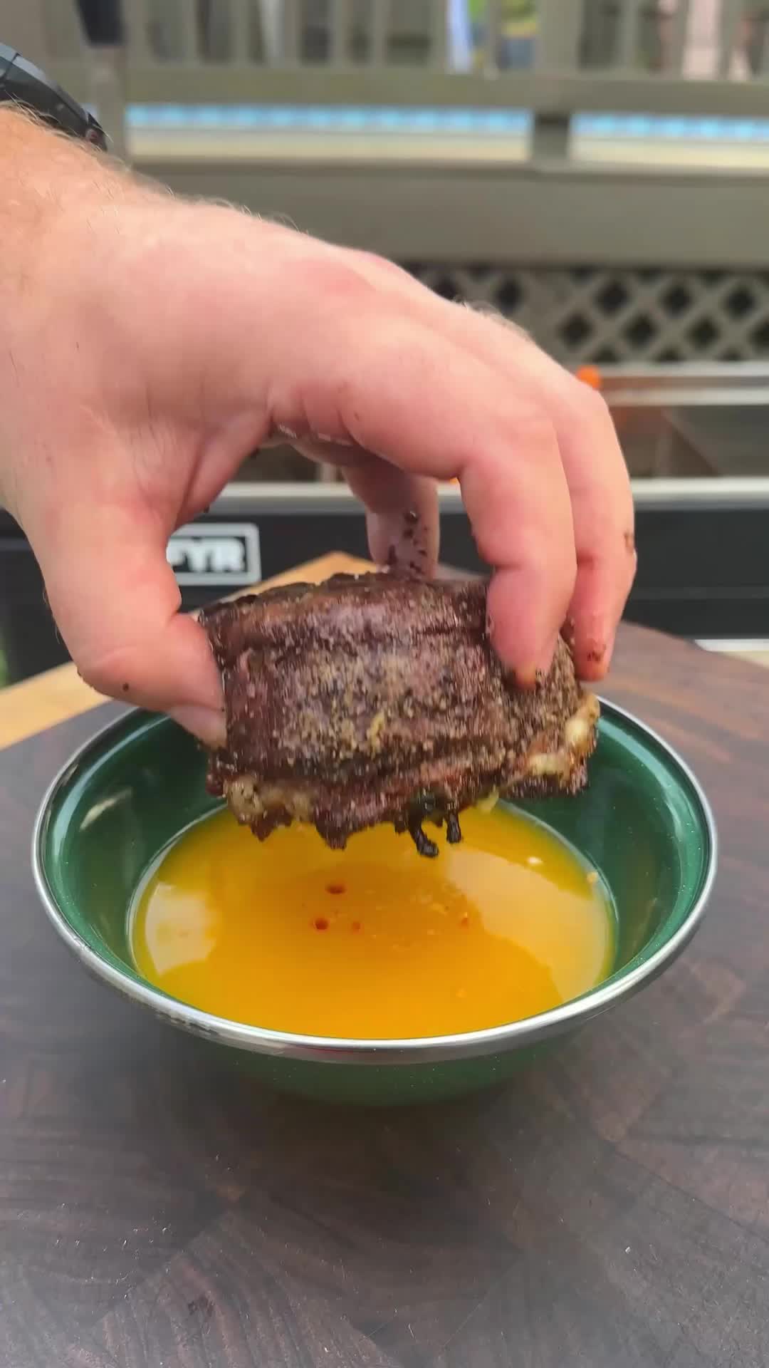 This may contain: a person is dipping sauce on top of a burger in a green bowl with mustard