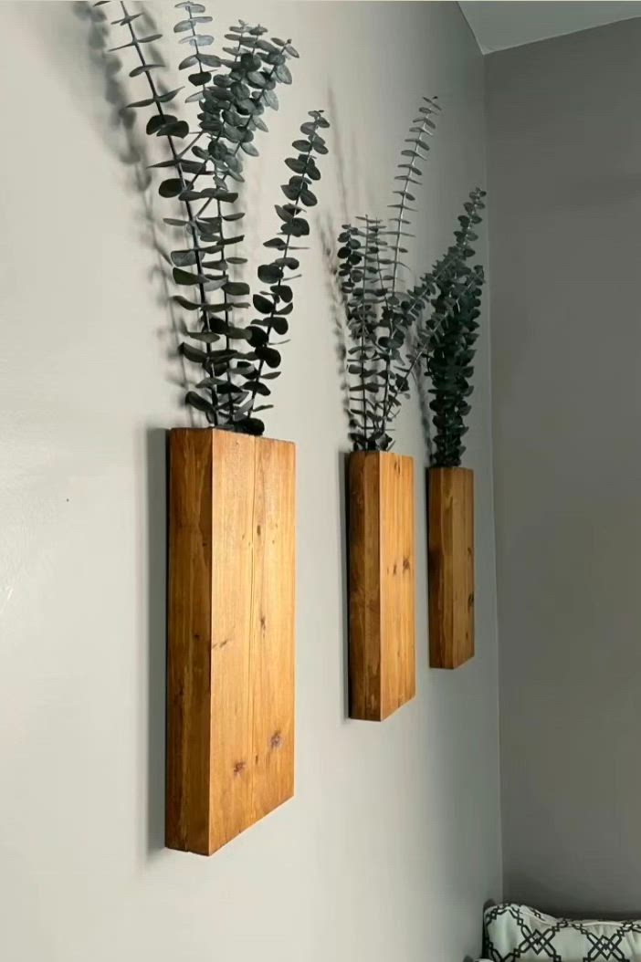 This may contain: two wooden vases with plants in them on the wall next to a bed and pillow