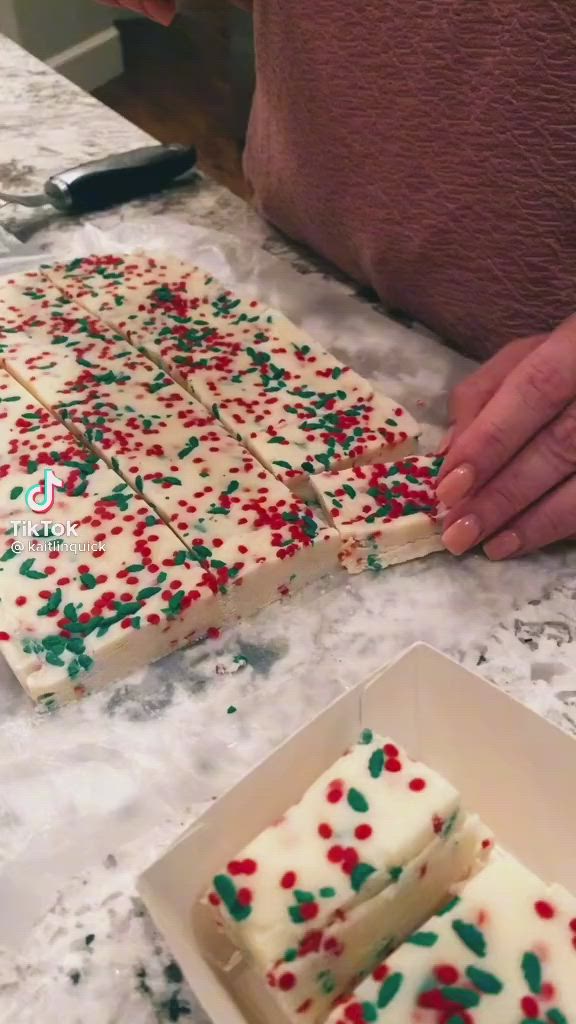 This may contain: someone is cutting up some cake with white frosting and sprinkles on it