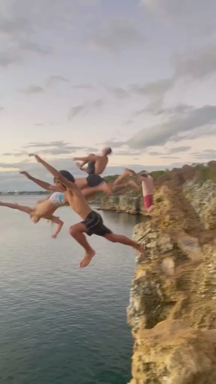 This may contain: three people jumping off a cliff into the water