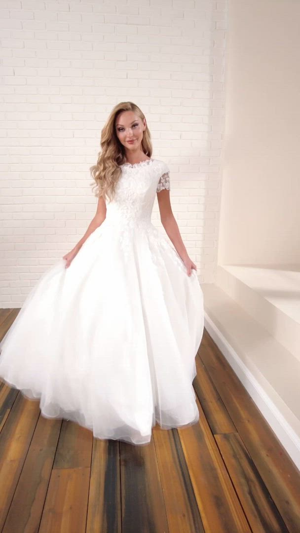 This may contain: a woman in a white dress is standing on a wooden floor and posing for the camera