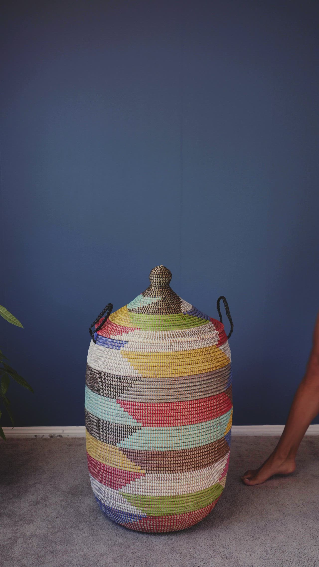 This may contain: a person standing next to a large woven basket on the floor in front of a blue wall