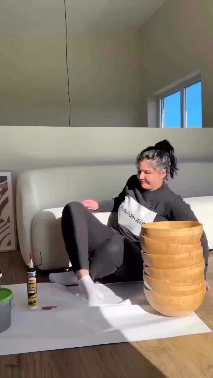 This may contain: a woman sitting on top of a white couch next to a stack of wooden discs