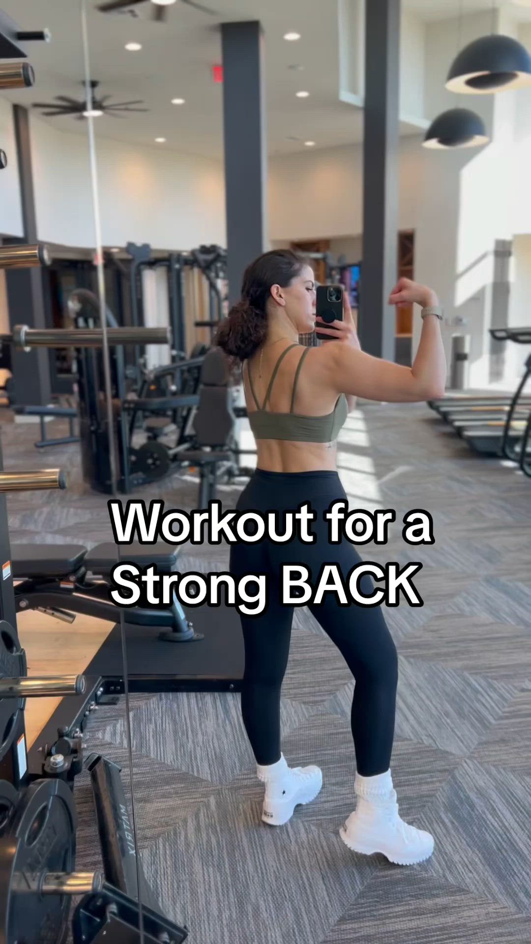 This may contain: a woman taking a selfie in the gym with her cell phone and text that reads, workout for a strong back