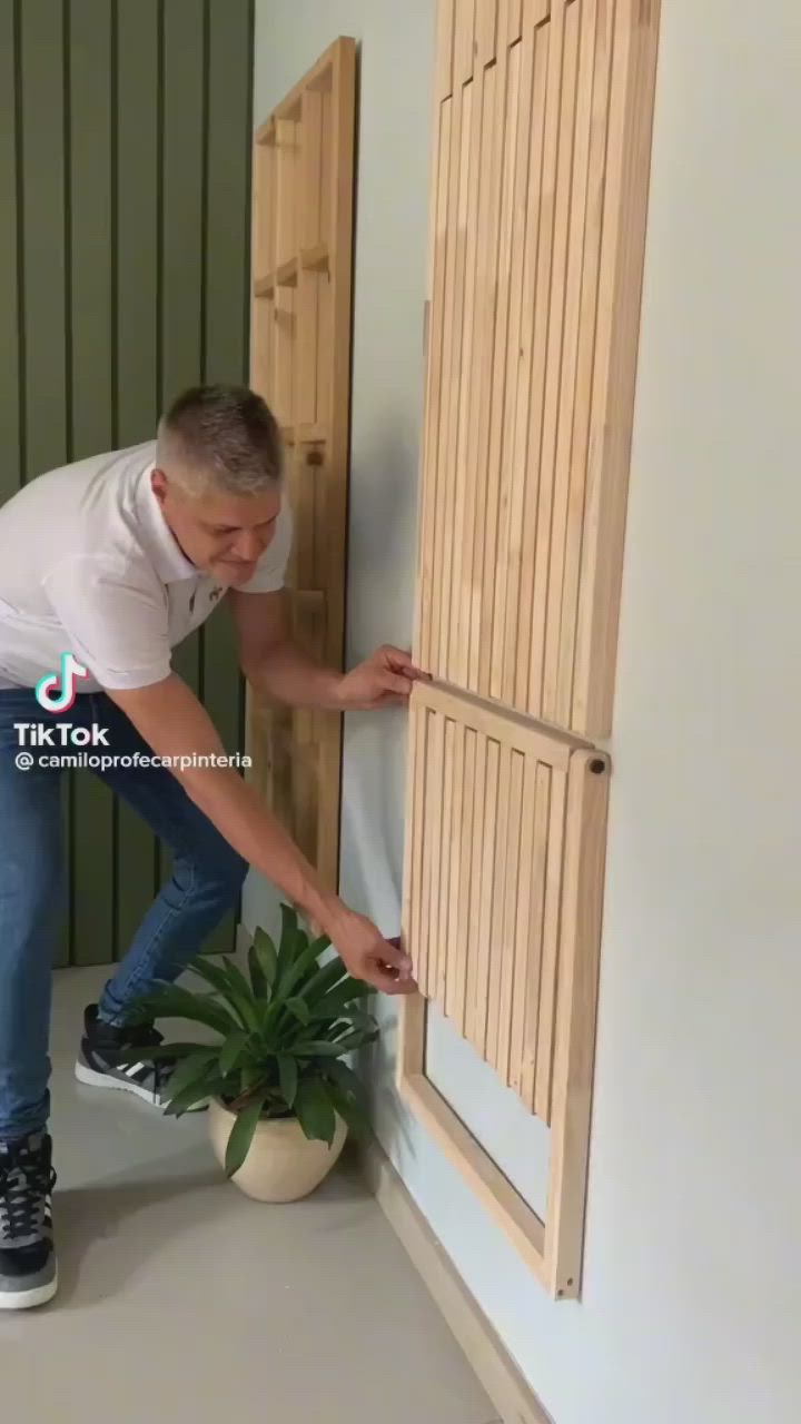 This may contain: a man standing next to a plant in front of a wooden door