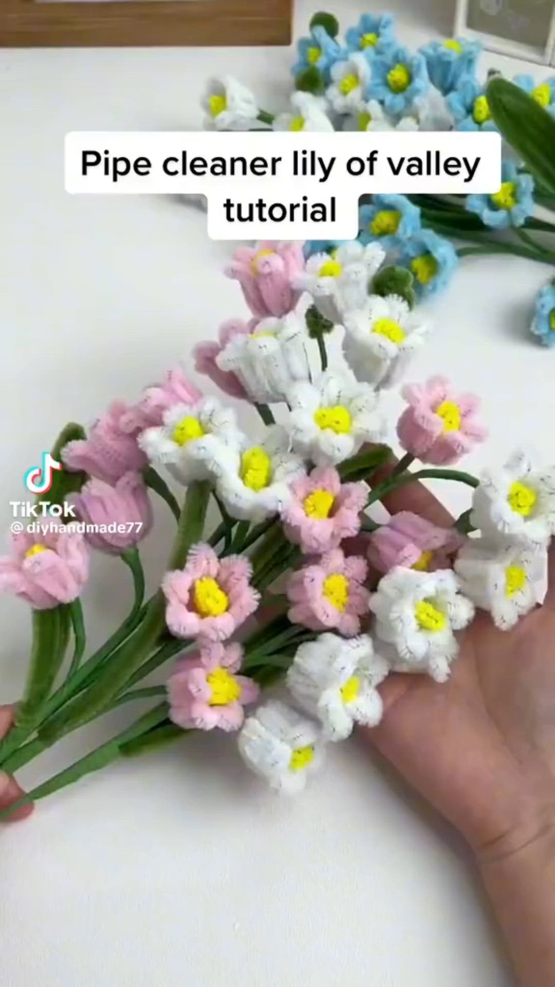 This may contain: a person is holding flowers in their hand with the words pipe cleaner lily of valley