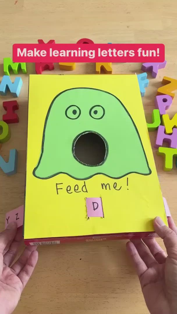 This may contain: two hands holding up a paper box with letters and a green monster on it that says, make learning letters fun