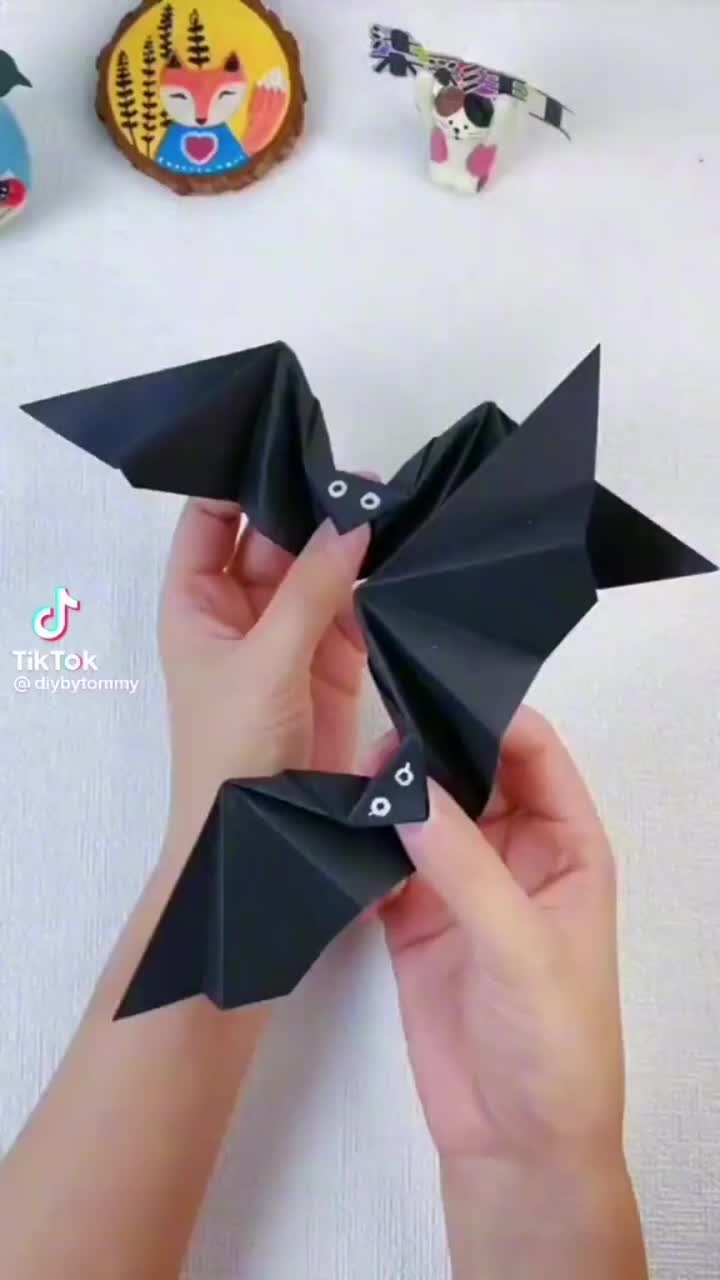 This may contain: someone is holding an origami bat in their hands