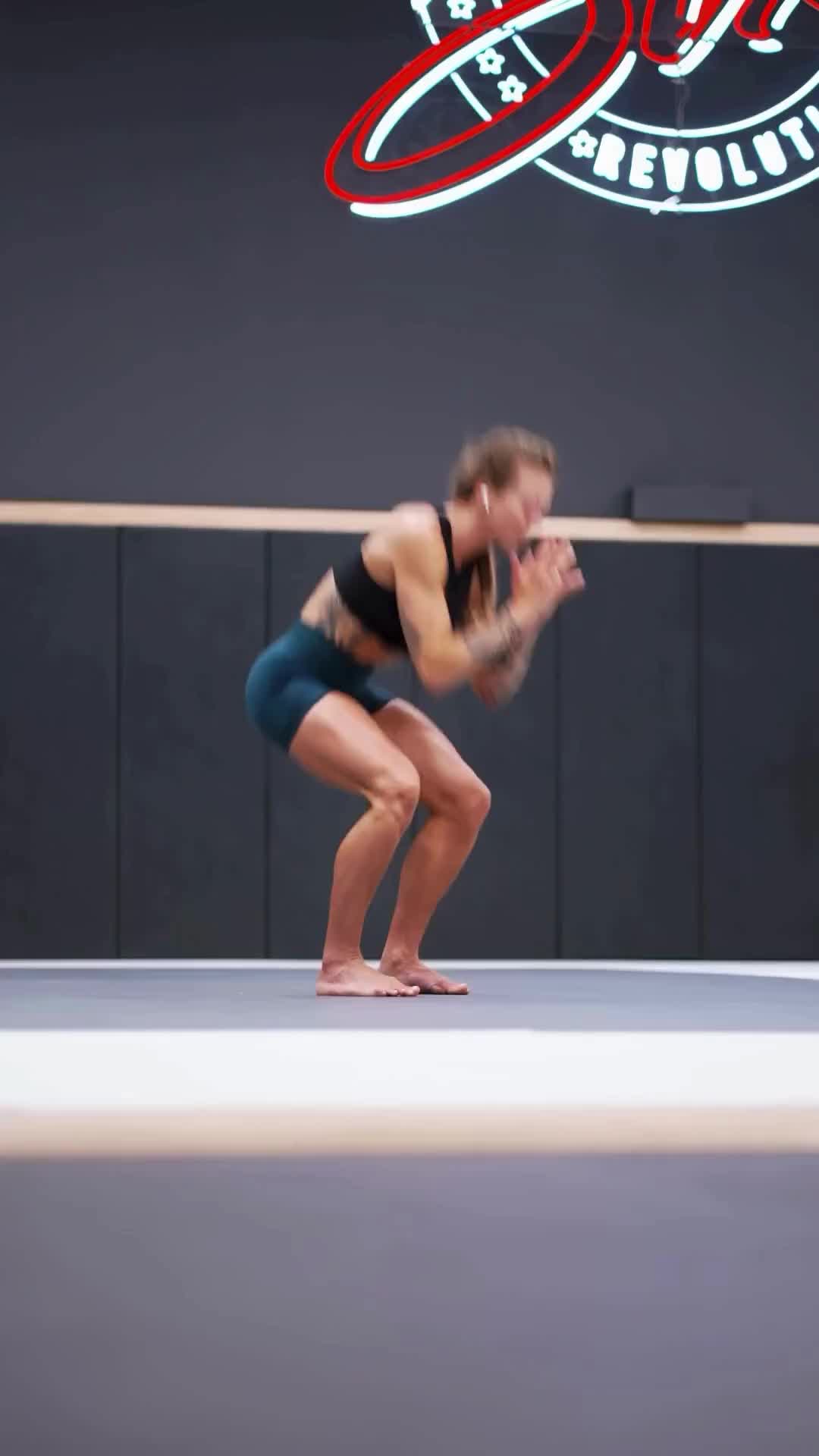 This may contain: a woman is doing a handstand on the floor in front of a sign