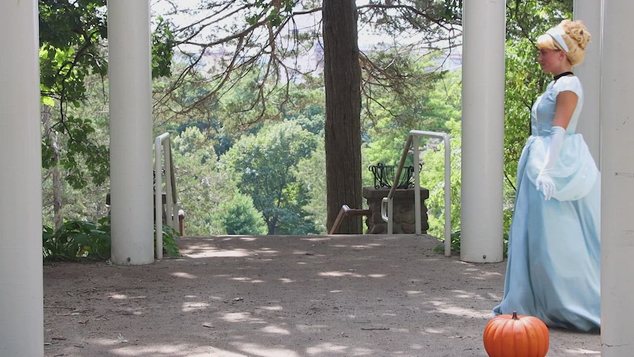 This may contain: a woman in blue dress standing next to an orange pumpkin