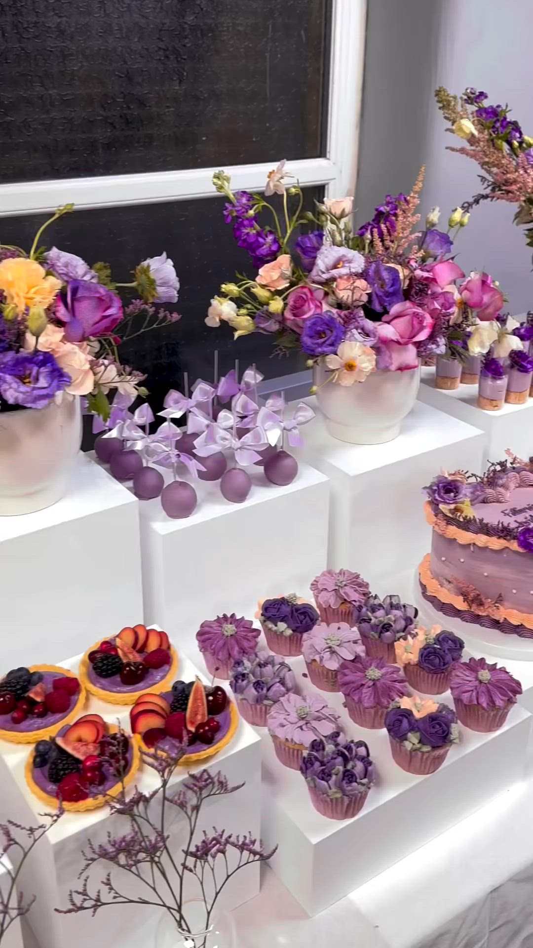 This may contain: a table topped with cakes and cupcakes covered in purple frosting