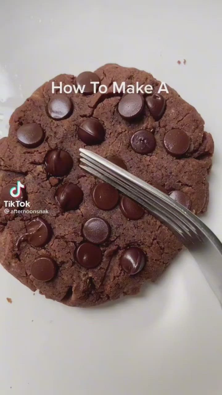 This may contain: a chocolate cookie on a white plate with a fork in it and the words how to make a microwave cookie