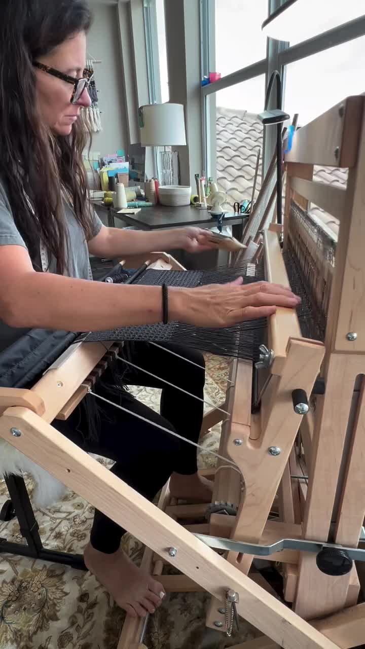 This may contain: a woman is weaving fabric on a loom