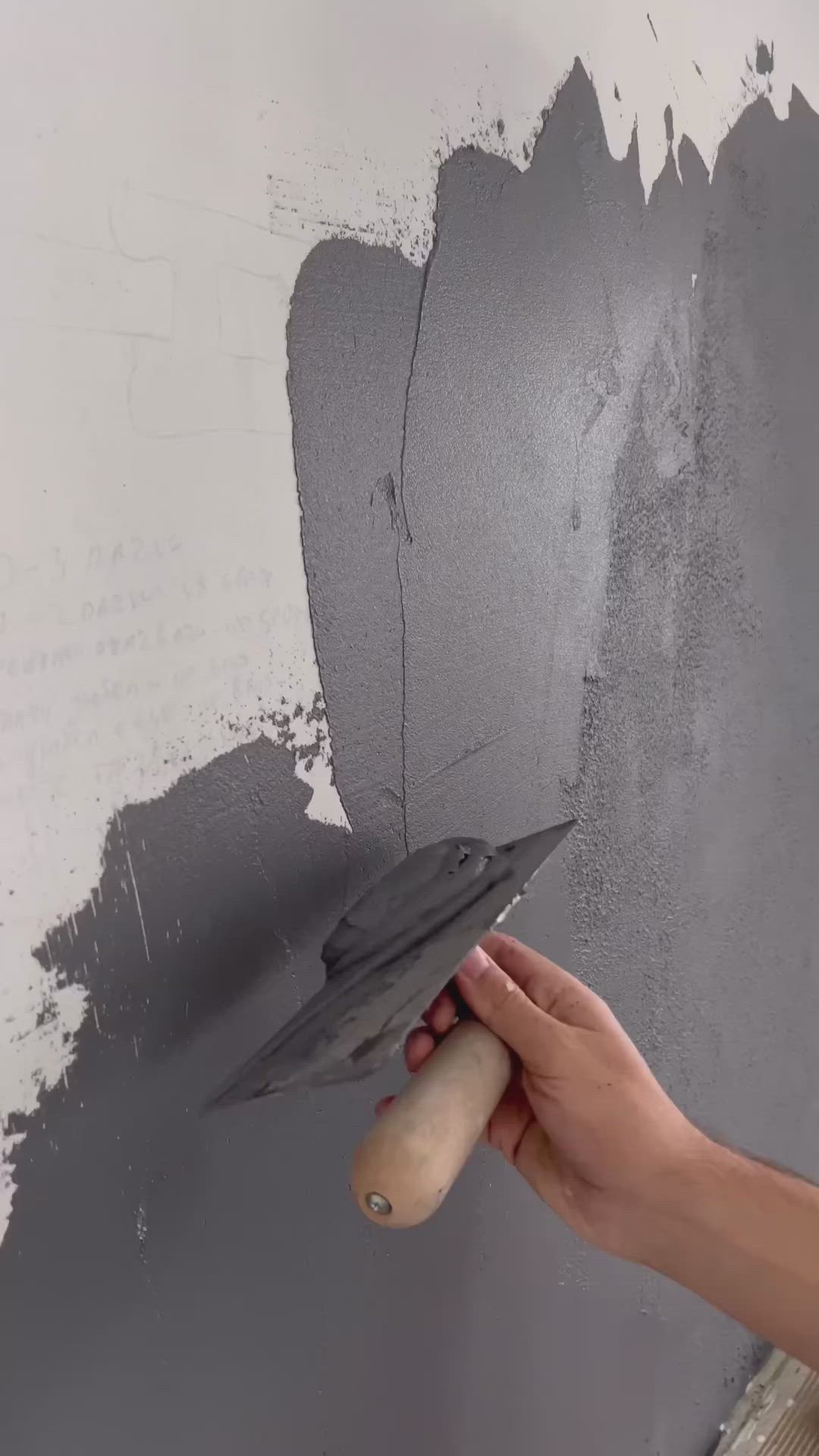 This may contain: a person is painting a wall with gray paint and an object in the middle of it