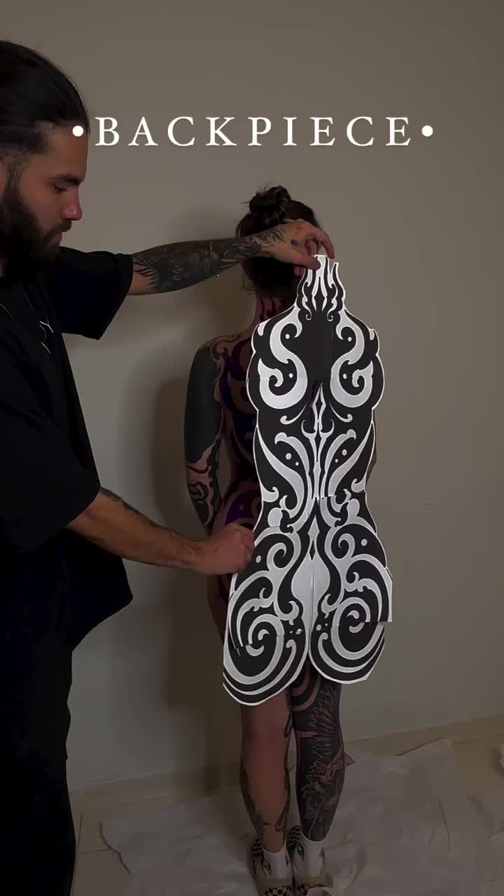 This may contain: a woman with tattoos standing next to a large piece of art that looks like a body