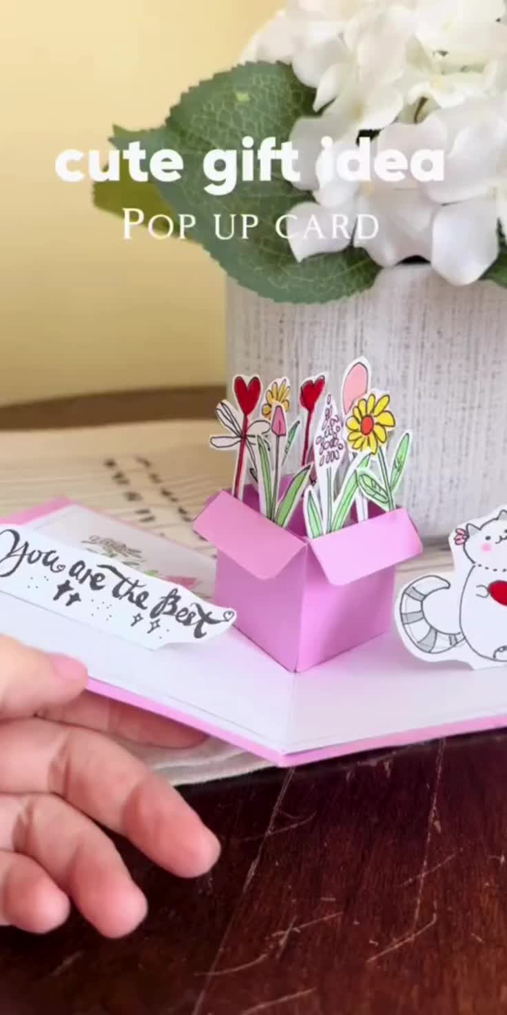 This may contain: someone is holding an open pop up card with flowers in it and the words cute gift idea