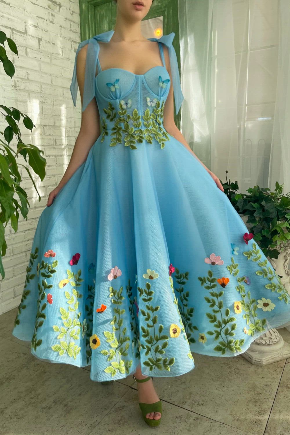 This gorgeous baby blue dress features a stunning combination of mesh-net and tulle fabric. The corset has built-in pads and boning, and the bust is draped. The dress also has inseam pockets, decorative bow straps, and an embelished garden embroidery bottom skirt with green leaves at the waist and powder butterflies.