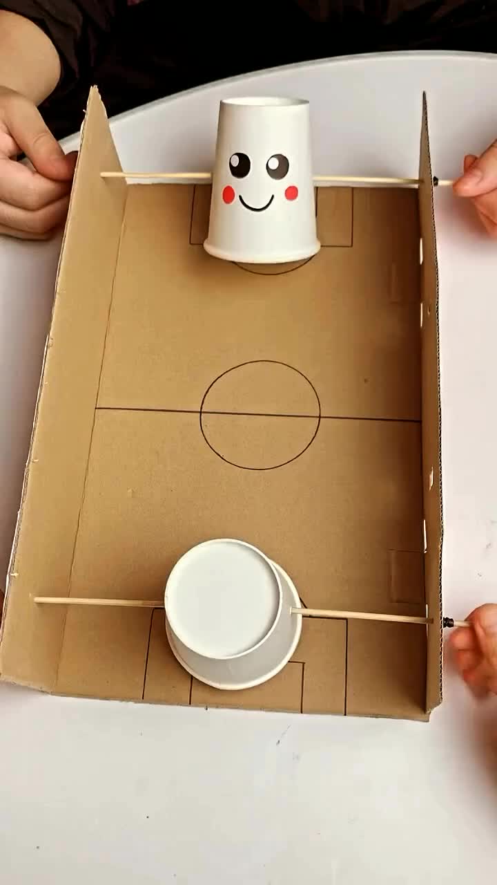 This may contain: a cup sitting on top of a cardboard box with a face drawn on the side