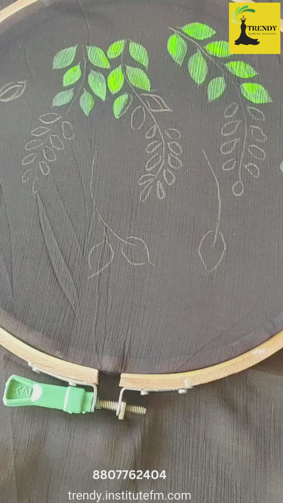 This may contain: the embroidery is being stitched on to a piece of fabric with green and white leaves