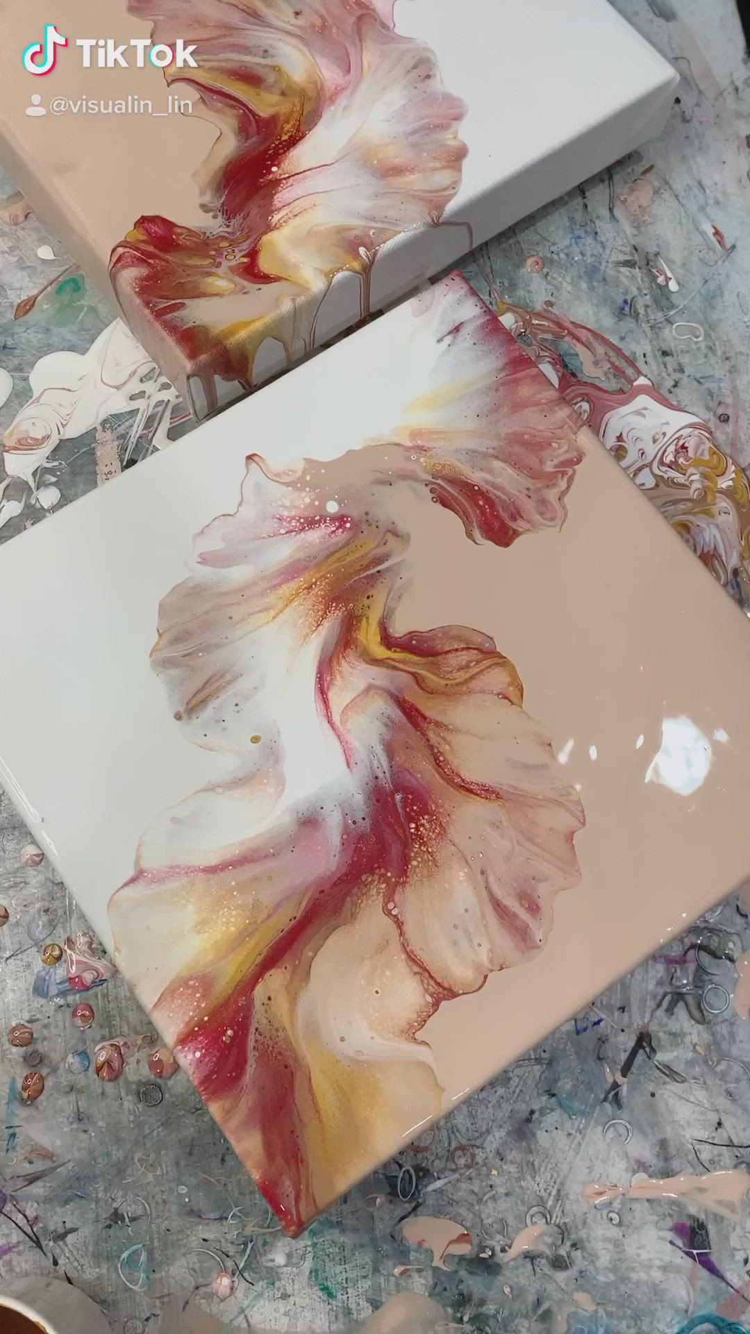 This may contain: two laptops sitting on top of a table covered in paint and paper with flowers painted on them