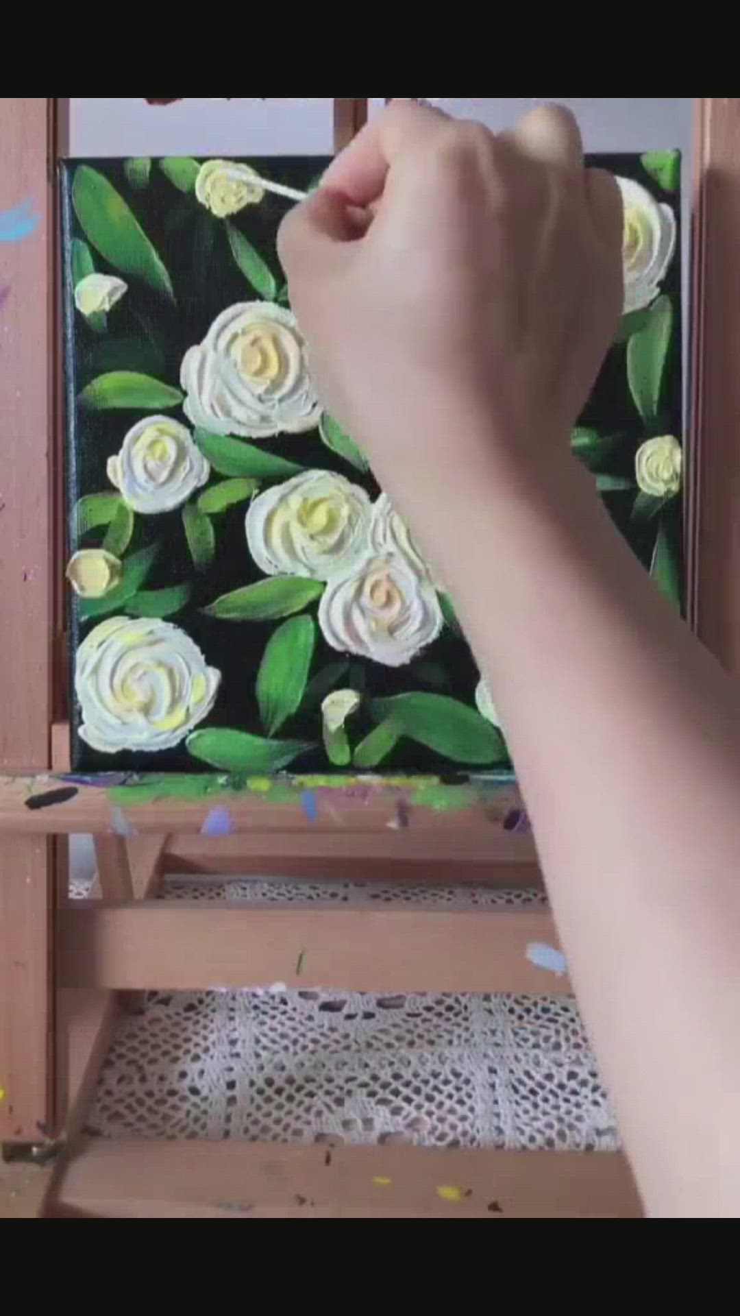 This may contain: someone is painting white roses on a canvas