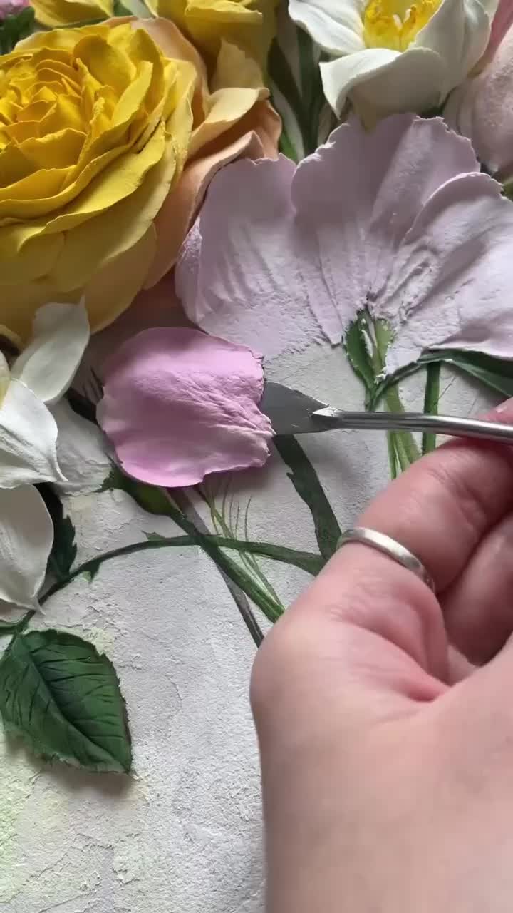 This may contain: a person cutting flowers with scissors on a white tablecloth covered in pink and yellow flowers