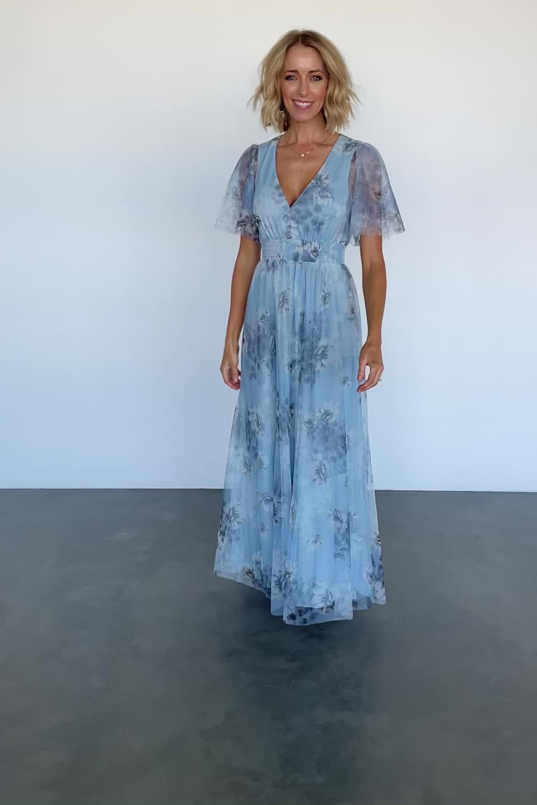 Baltic Born exclusive style Flowy tulle material Soft light blue color with muted florals Smocked waist Double layered flutter sleeves Deep V neckline Maxi length skirt Fully lined bodice and skirt Bump friendly Trina is 5'6, cup size 32D, size 2 and is wearing size S