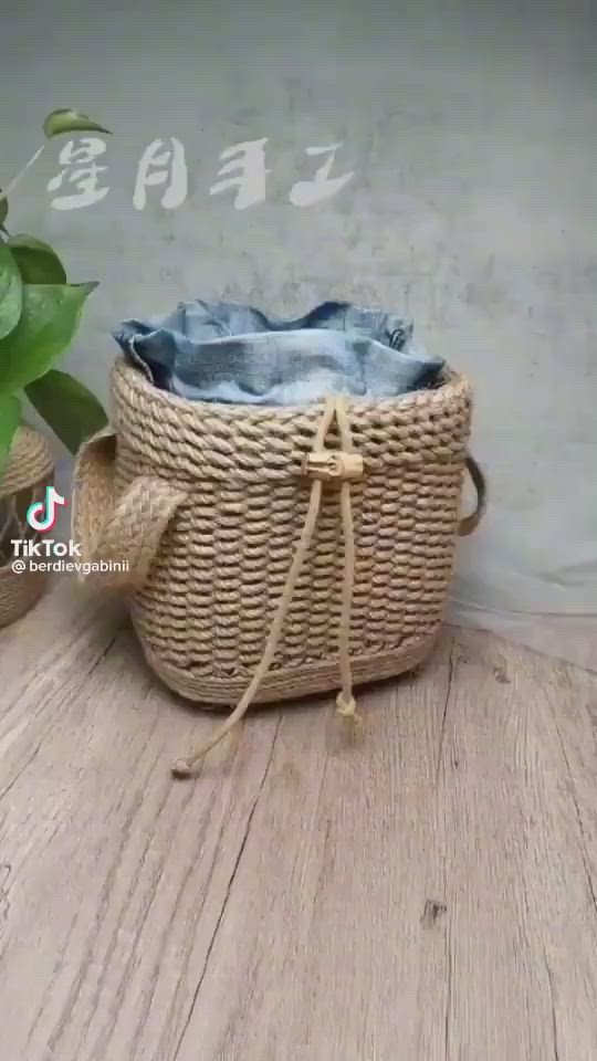 This may contain: two hands are holding a piece of woven material over a basket on a wooden table