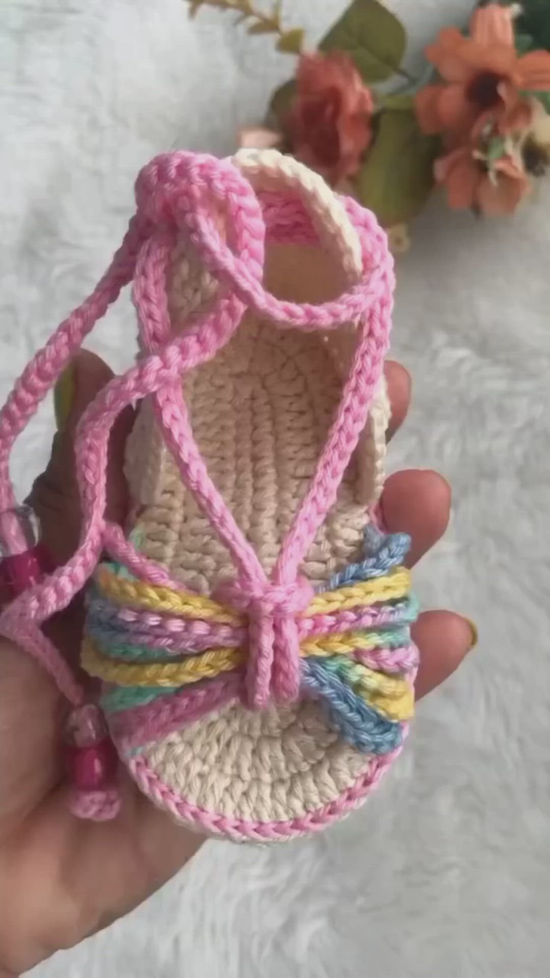 This may contain: someone is holding up a crocheted baby shoe