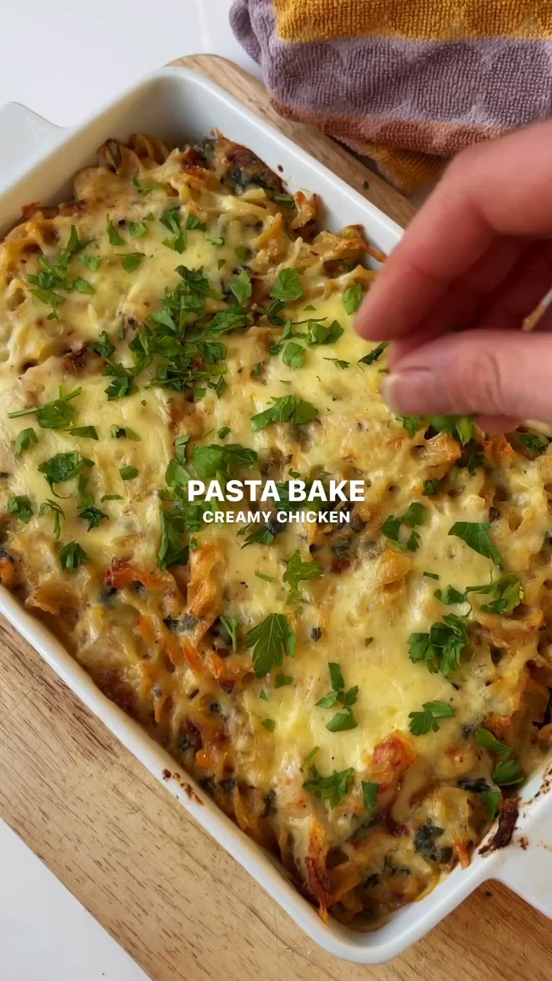 This may contain: a hand reaching into a casserole dish with cheese and herbs