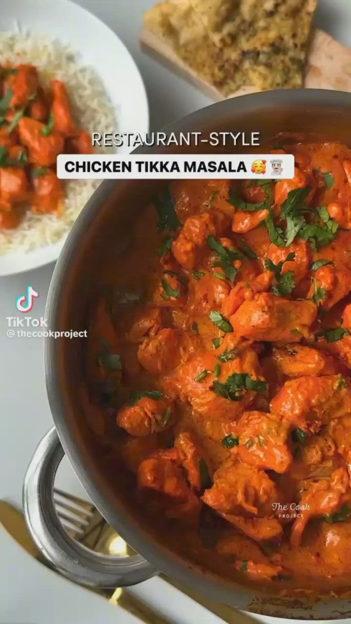 This may contain: chicken tikka masala in a pan with rice on the side