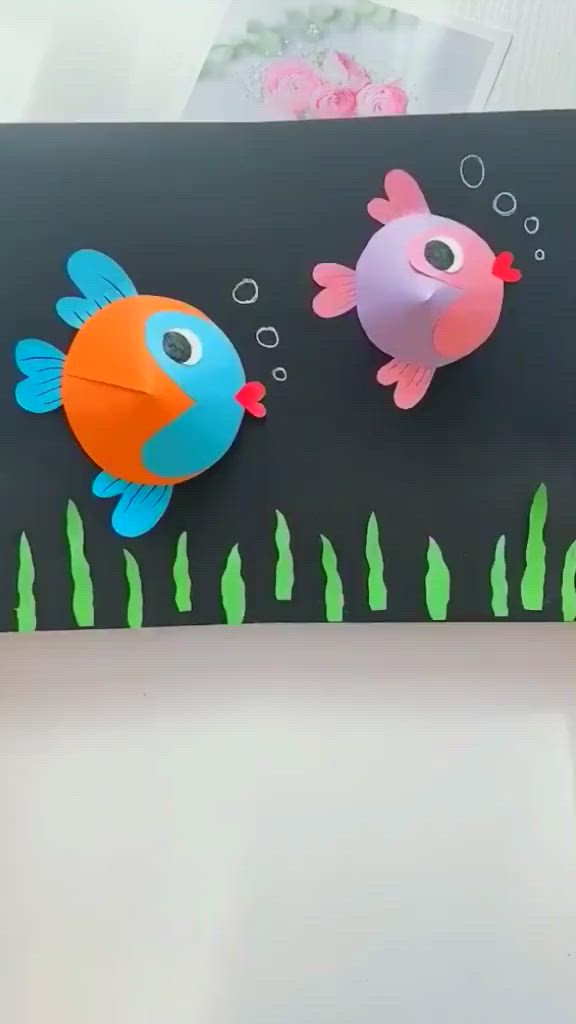 This may contain: two paper fish on a black board with seaweed