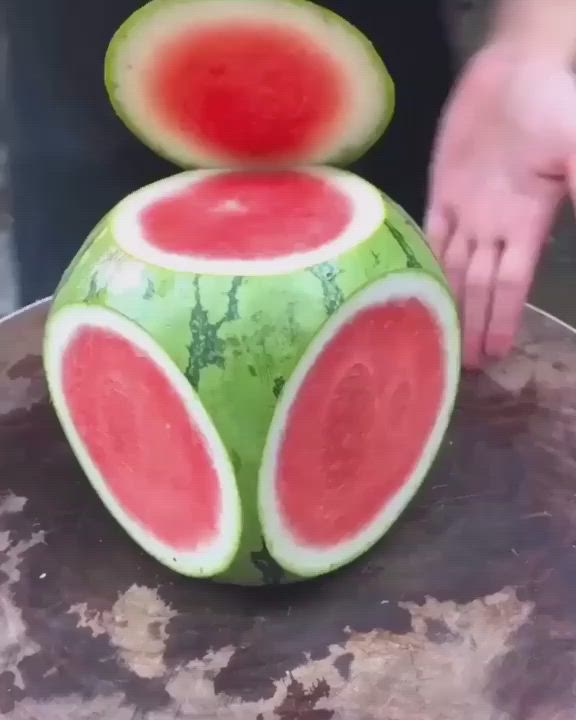 This may contain: a person cutting into a watermelon fruit sculpture