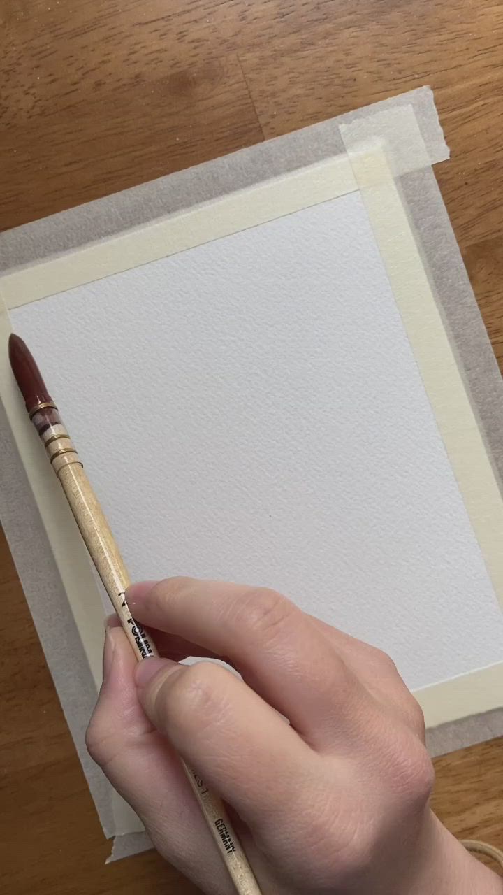 This may contain: a person is holding a paintbrush and drawing on paper with watercolor pencils