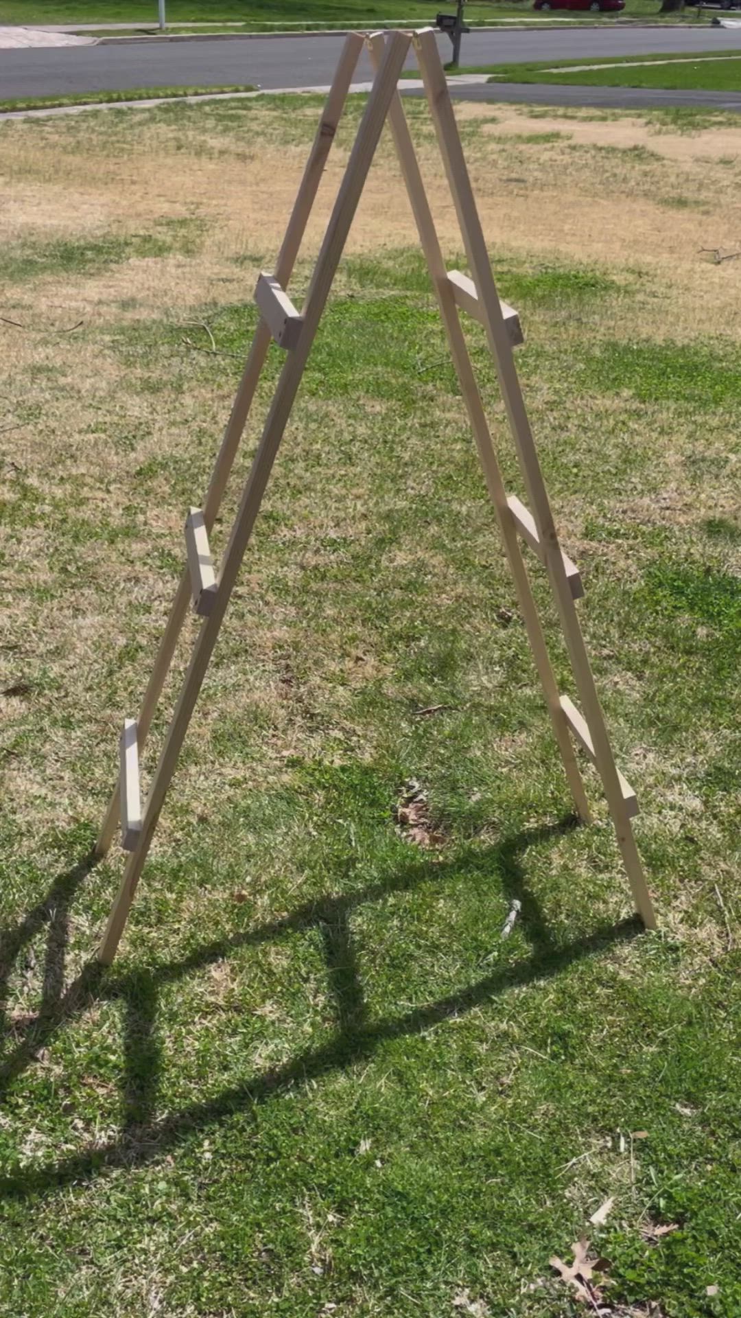 This may contain: a wooden ladder sitting on top of a lush green field