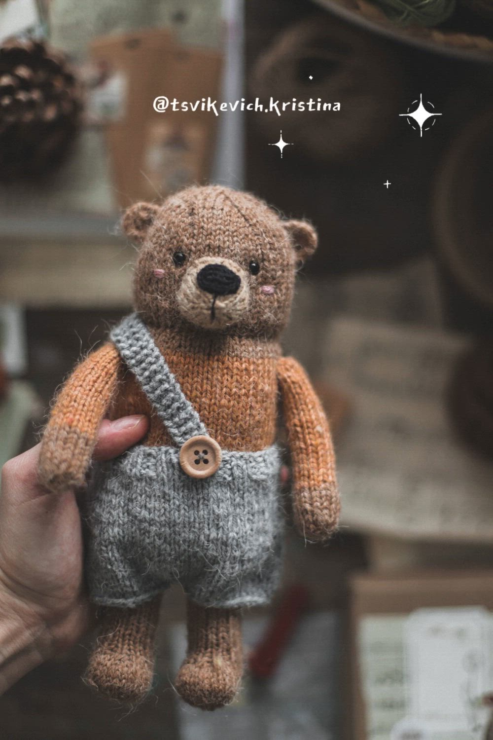 This may contain: a person holding a small teddy bear in their left hand and wearing a knitted outfit