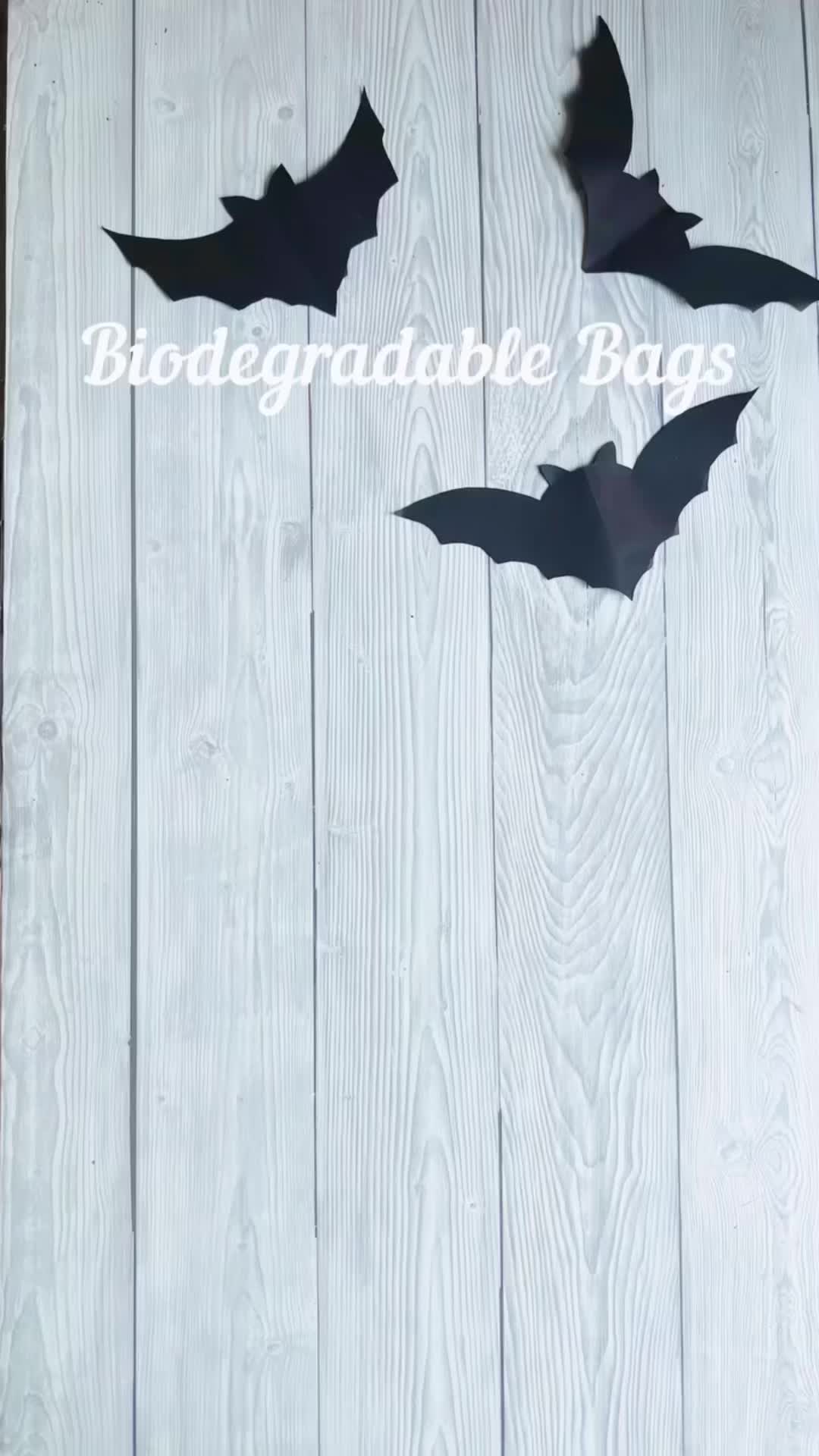 This may contain: three bats cut out of paper sitting on top of a wooden table