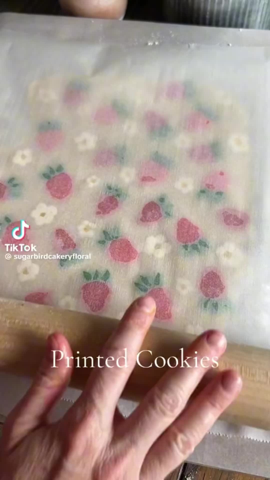 This may contain: someone is working on something that looks like fabric with strawberries and daisies printed on it