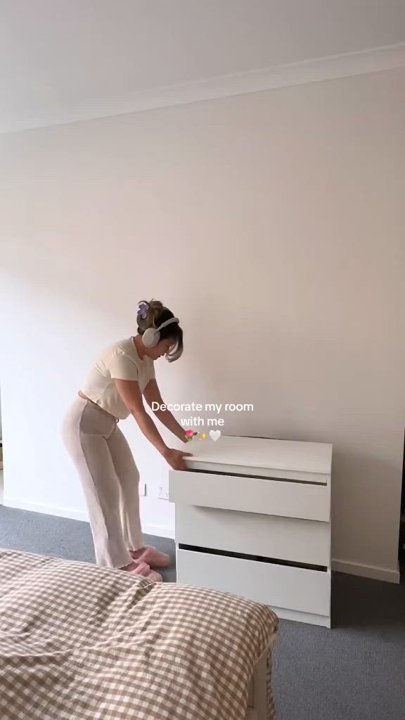 This may contain: a woman standing on top of a white dresser next to a bed in a bedroom