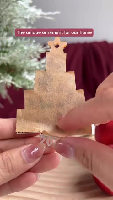 This may contain: two hands holding a piece of wood with the words, the unique ornament for our home