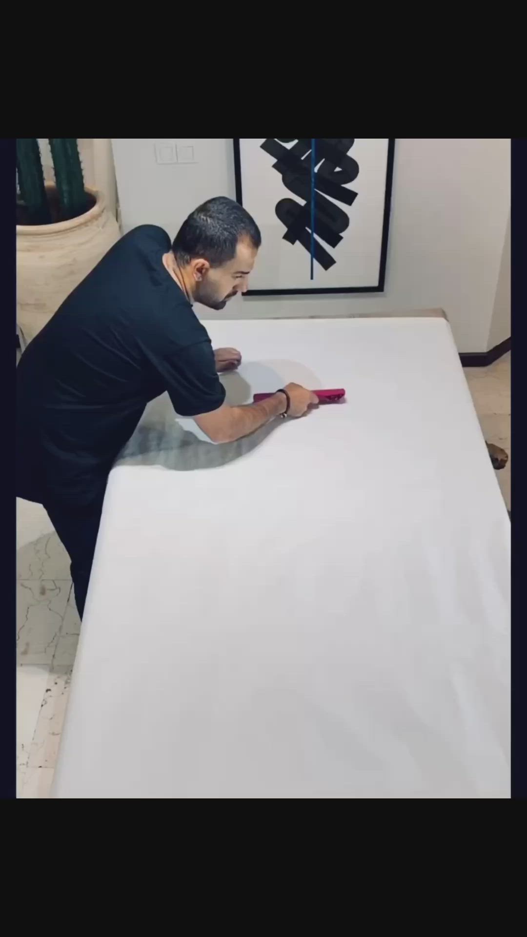 This may contain: a man is painting a piece of art on a white surface with black paint and brush