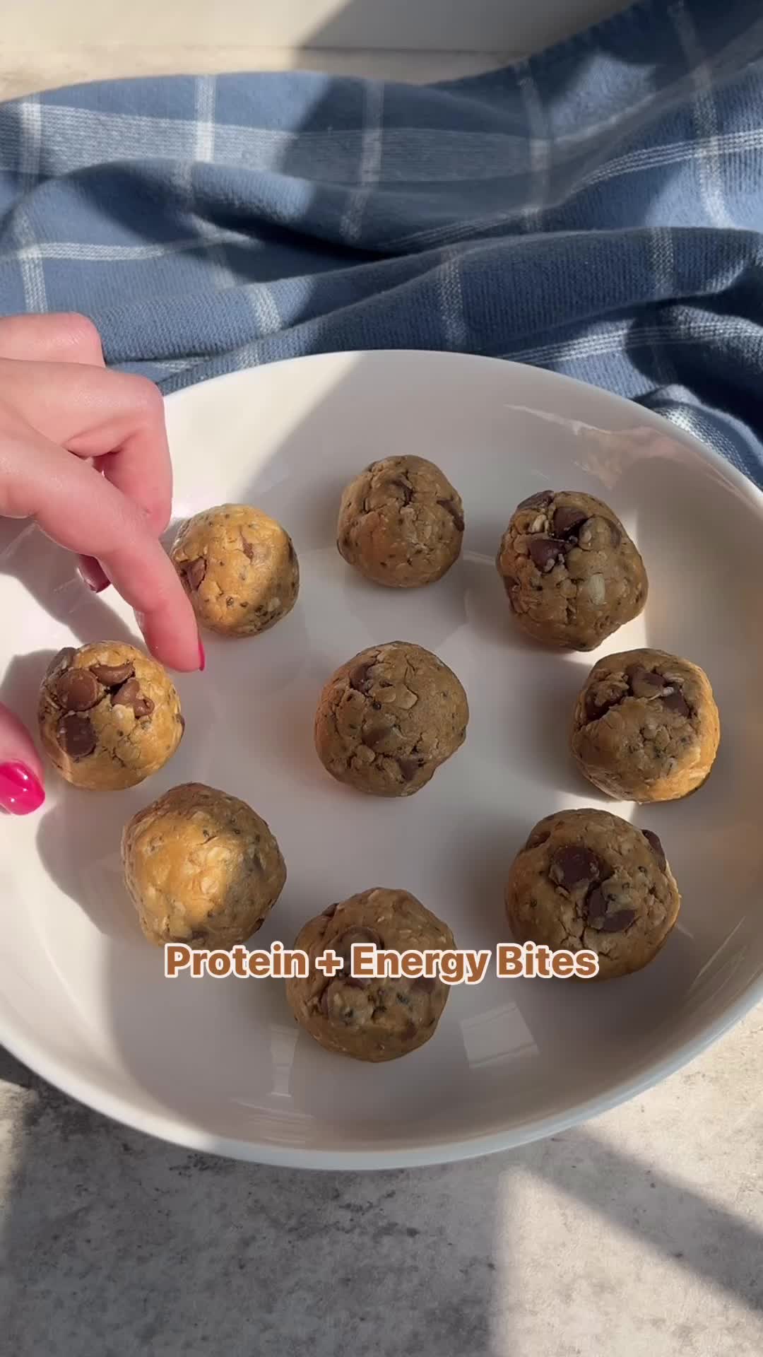 This may contain: a person picking up some chocolate chip cookies on a plate